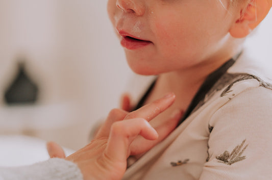 A young mother applies all-natural breathe well salve to the chest of a young boy to help breathing