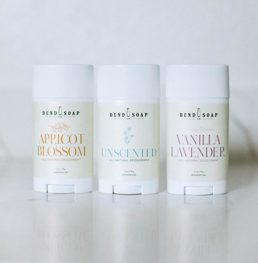 Three Bend Soap Company's Magnesium Deodorant (Baking Soda Free) Variety Pack is shown, with sticks in Apricot Blossom, Unscented, and Vanilla Lavender scents, all in white packaging with colored text and featuring magnesium hydroxide for odor protection.