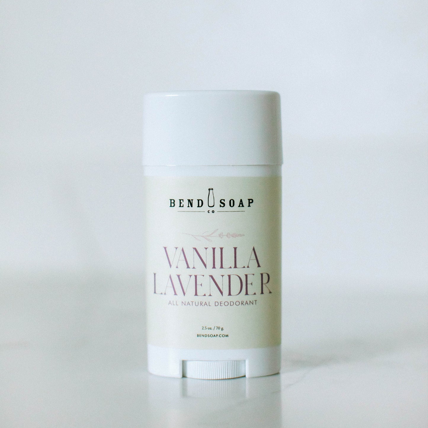 A white stick of Bend Soap's Magnesium Deodorant (Baking Soda Free) Variety Pack in Vanilla Lavender stands upright against a minimalistic background, offering gentle odor protection with magnesium hydroxide.