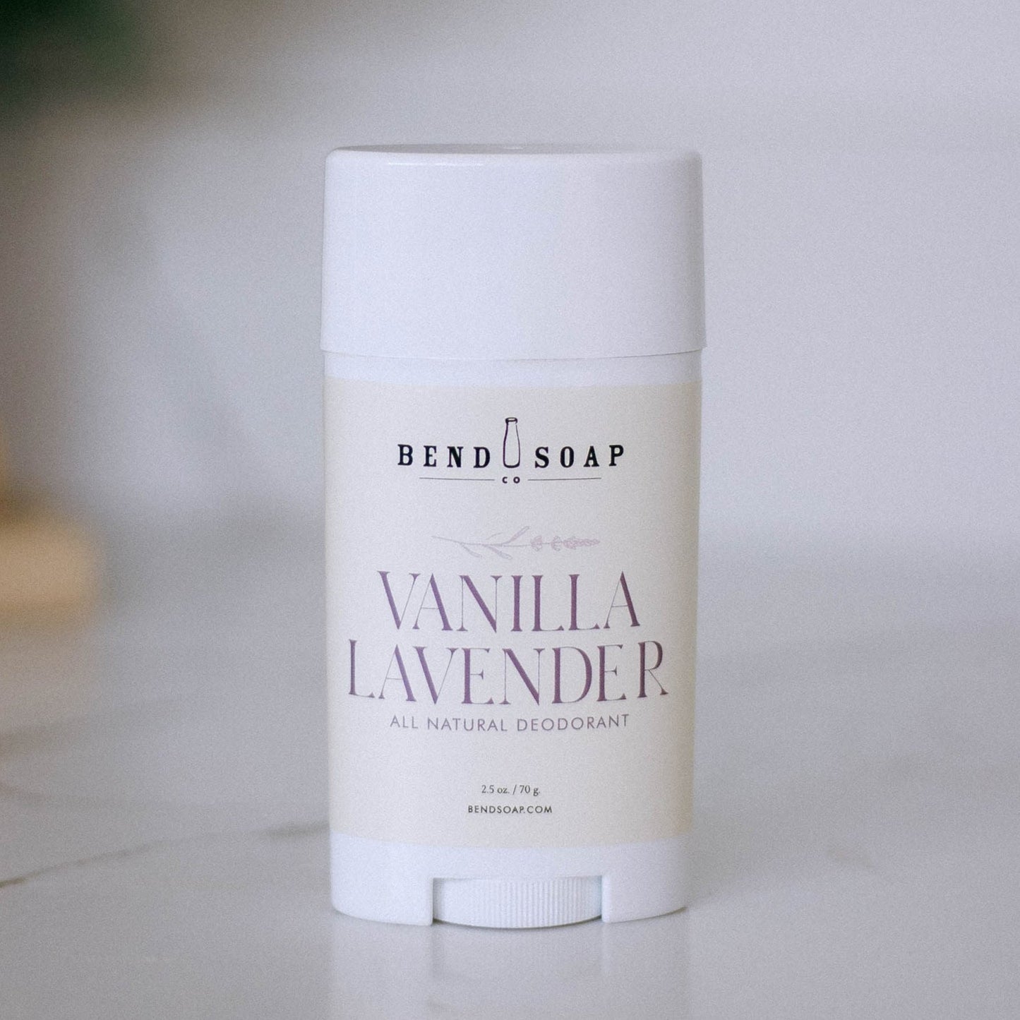 A white deodorant stick labeled "Vanilla Lavender Magnesium Deodorant (Baking Soda Free)" rests on a light marble surface, highlighting its gentle, all-natural formula with magnesium hydroxide for odor protection.