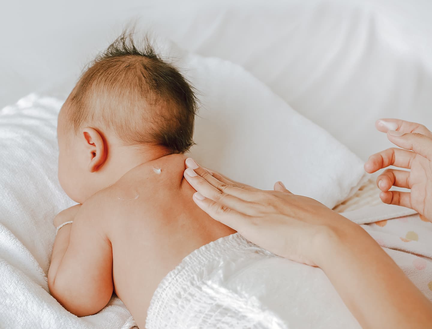 applying lotion to sensitive skin on a baby