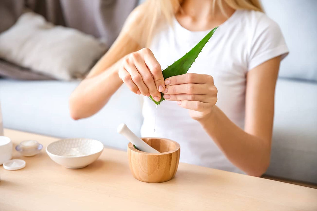 Woman using two hands to squeeze fresh aloe vera into bowl