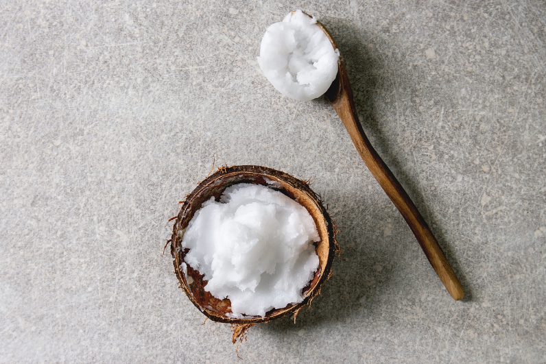 bowl of fresh coconut oil on a concrete background with a wooden spoon