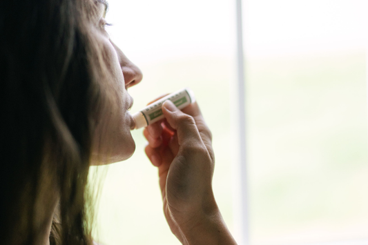 Applying natural lip balm to soothe dry, chapped lips