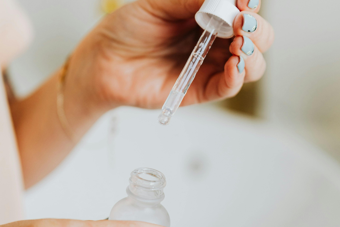Close-up of dropper applying salicylic acid for acne treatment into skincare bottle