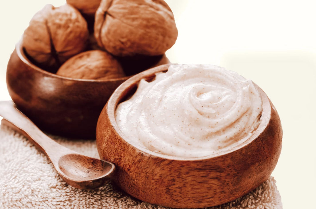 natural walnut scrub in a wooden next to a bowl full of walnuts on a tan towel 