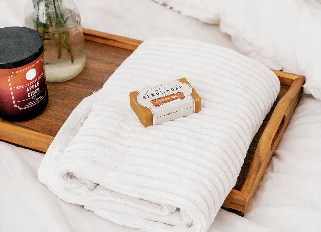 Bar of Tangerine Goat Milk Soap Laying on a Towel Folded On Top of a Serving Tray