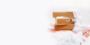 3 full size bars of chai tea goat milk soap stacked with soap suds foaming ontop