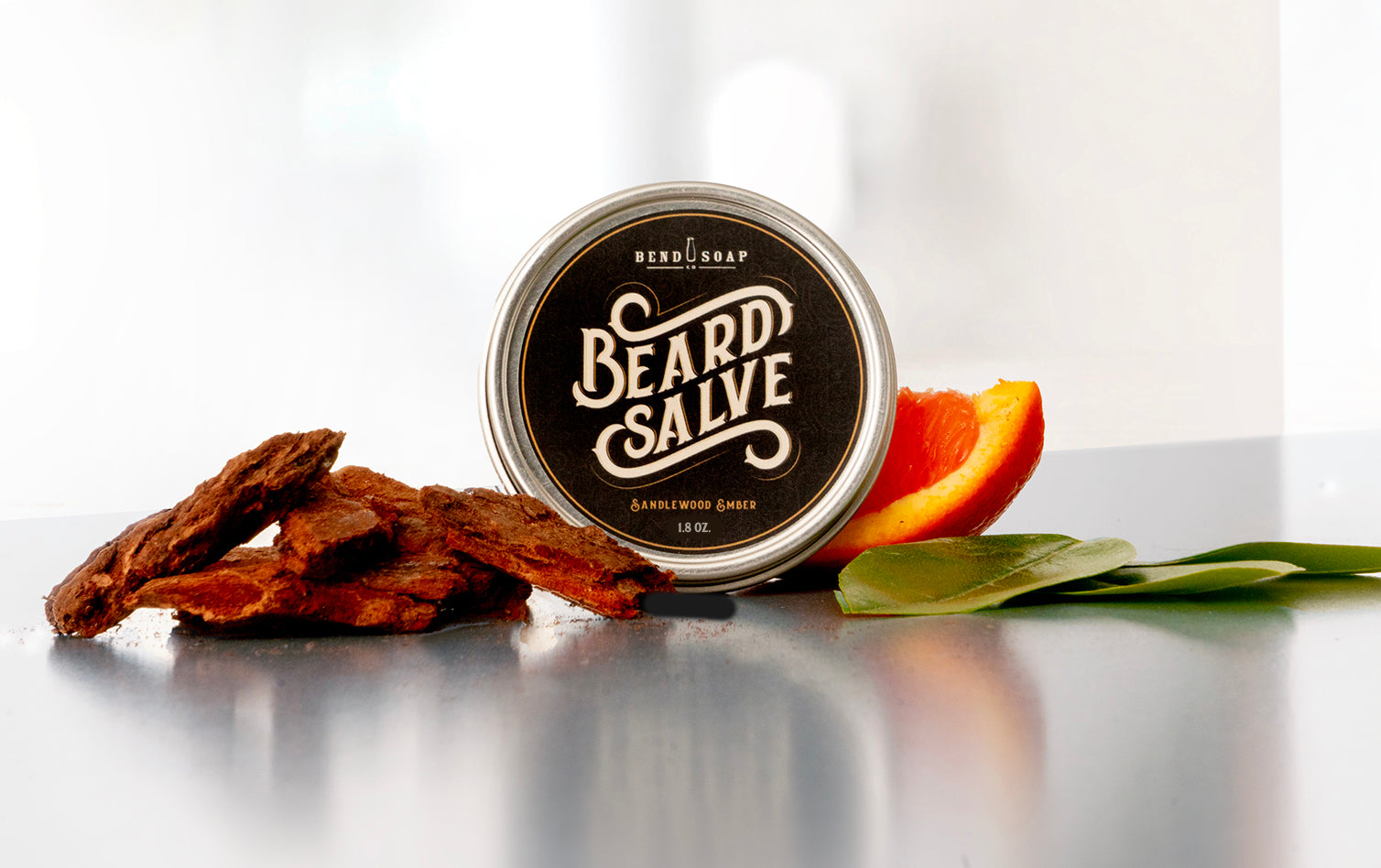 A tin of all-natural beard salve with sandalwood, orange and tea tree on a counter