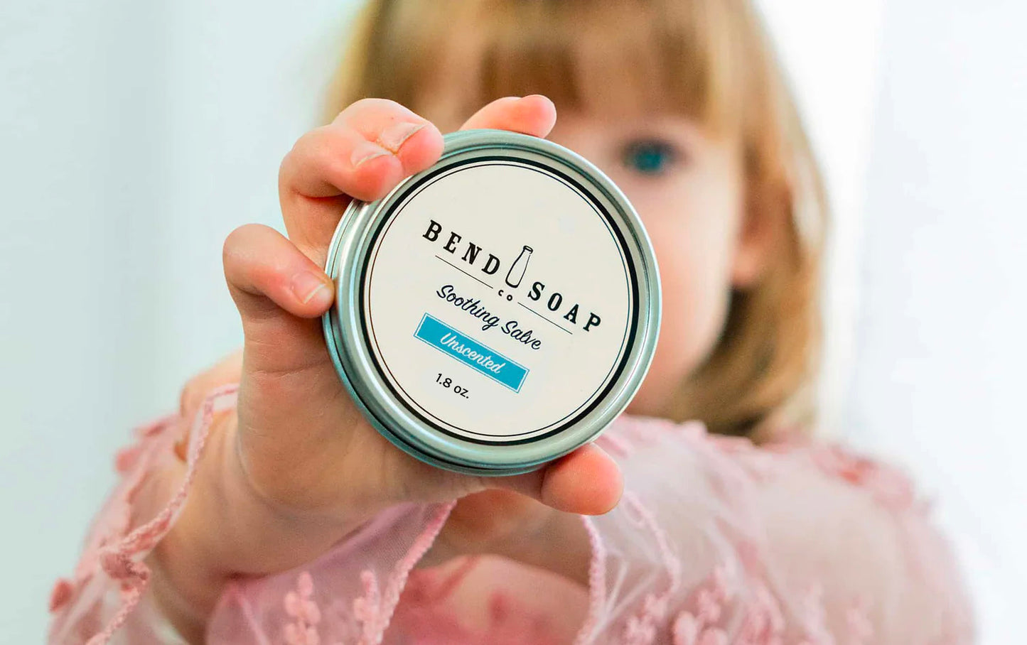 Little girl holding a tin of Unscented Soothing Salve