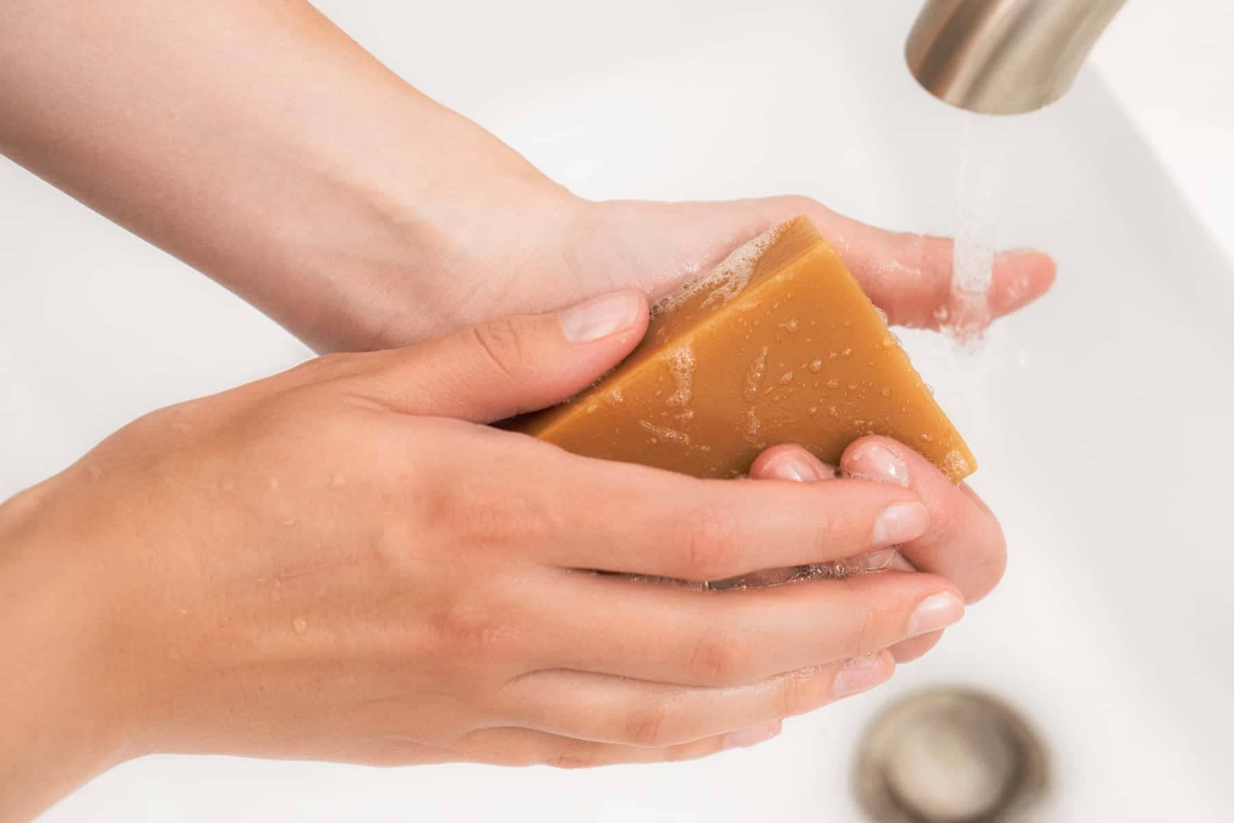 Woman washing her hands with a bar of all shield goat milk soap