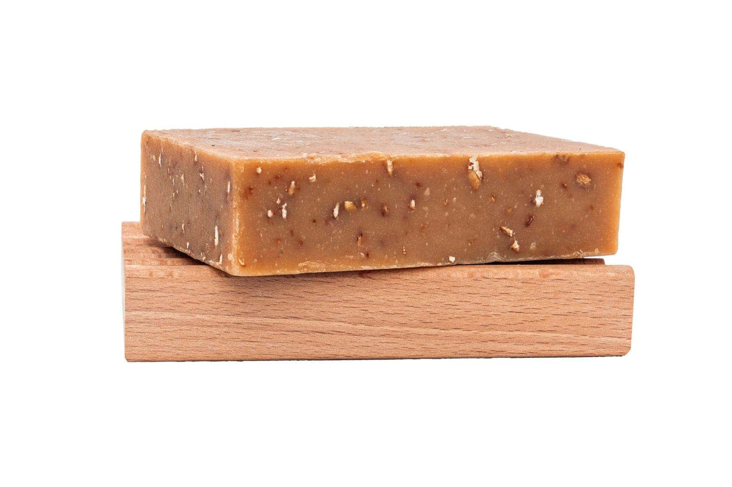 Unwrapped bar of oatmeal and honey goat milk soap on an all natural wood soap dish